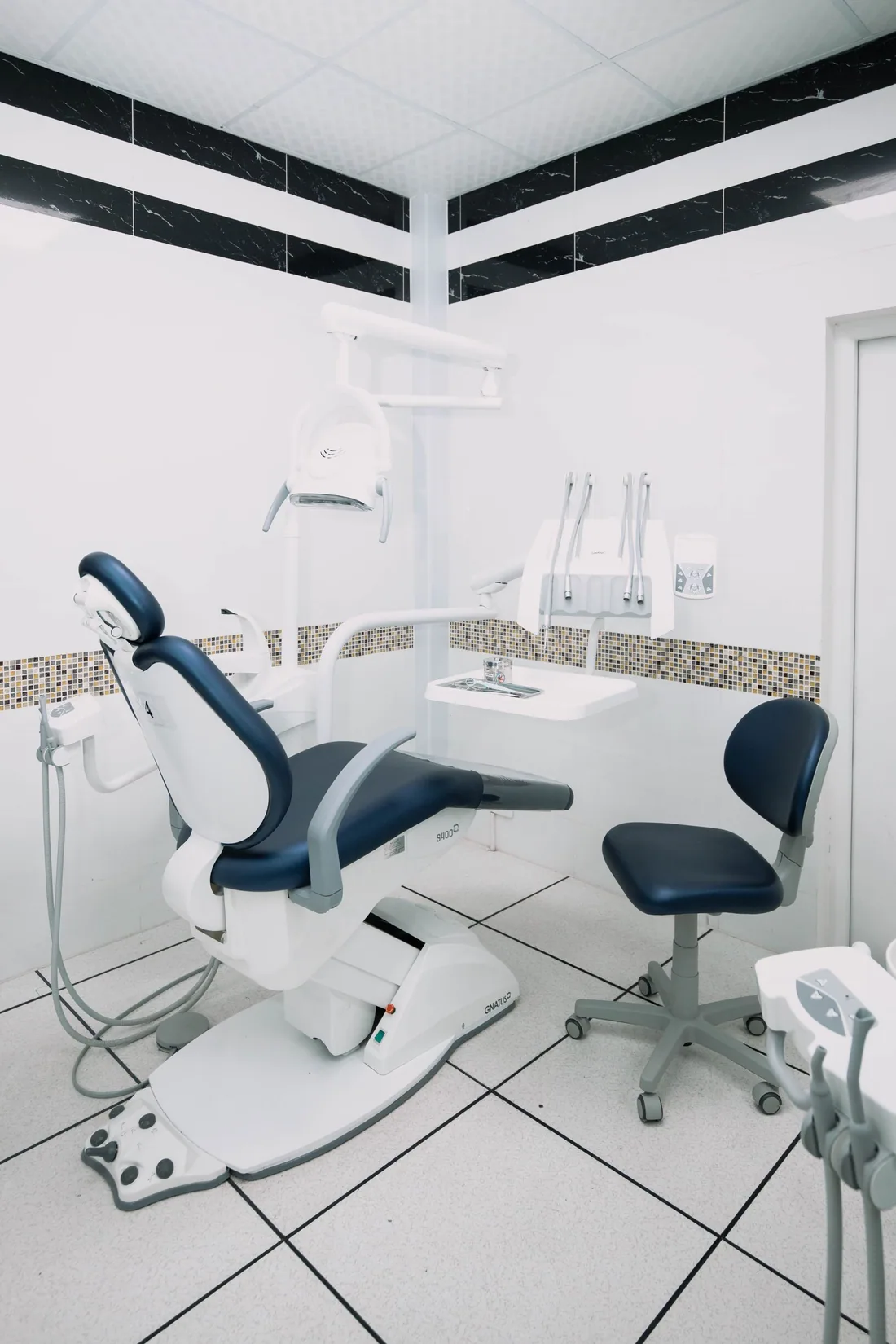 An empty dental treatment room with a patient chair and clinical equipment